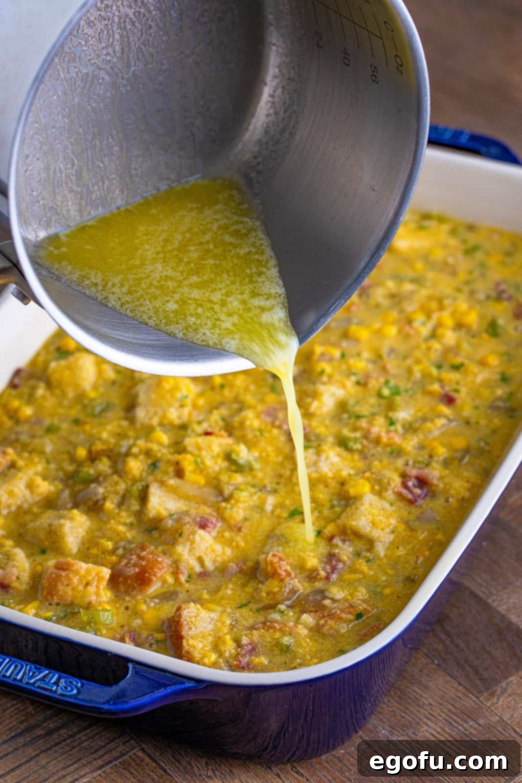 Melted butter being poured over dressing mixture in baking pan.