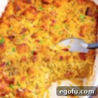 Close up square image of finished Southern Cornbread Dressing in baking pan with some removed and serving spoon in pan.