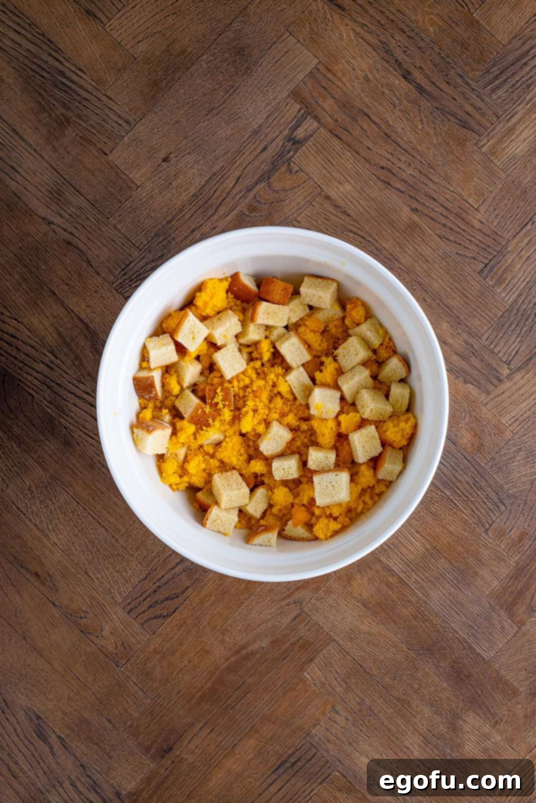 Cornbread and white bread added to large white bowl.