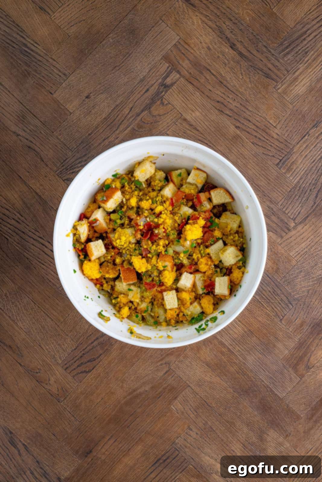Vegetables, bacon and seasonings added to bowl with breads.