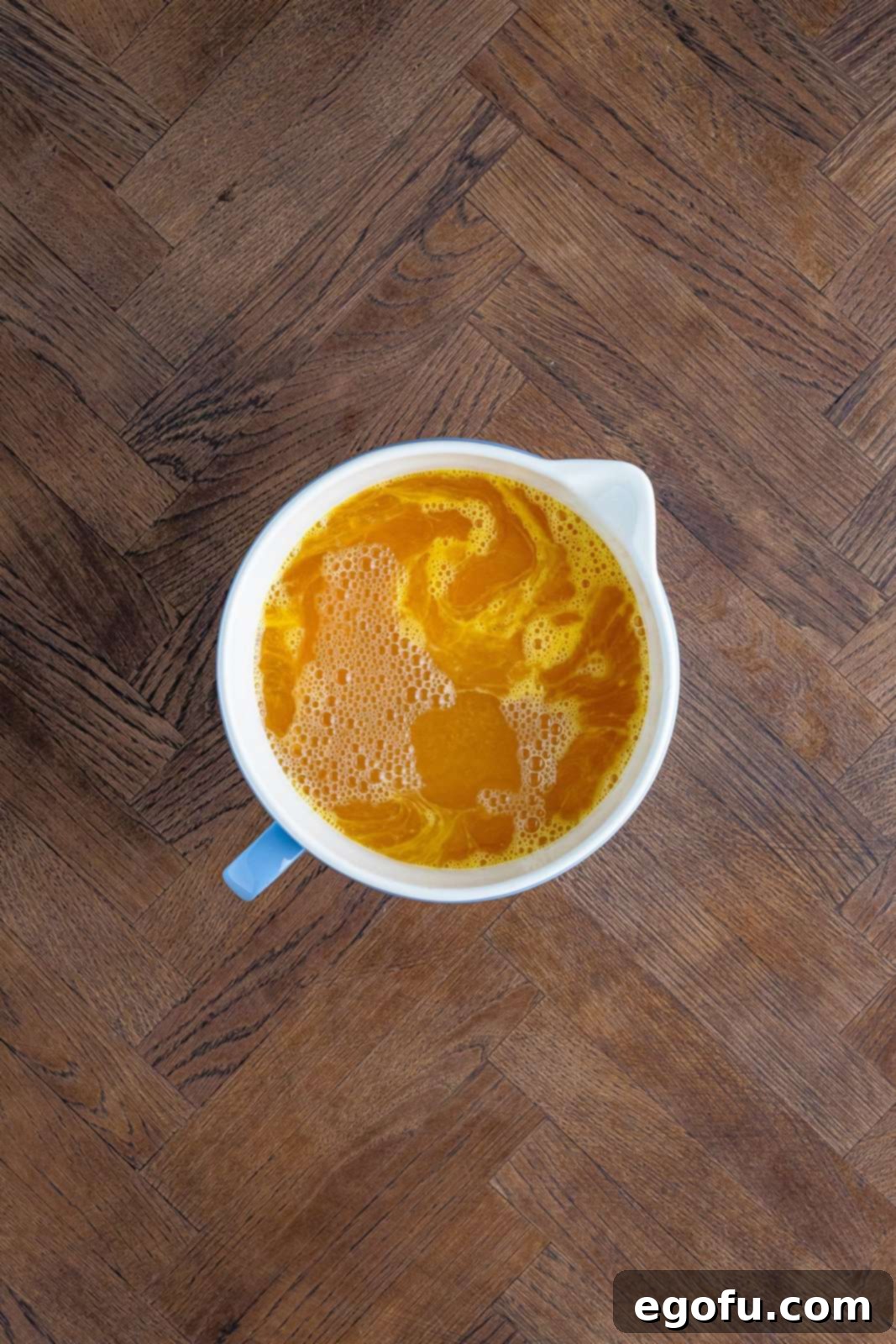 Creamed corn and chicken stock added to bowl with eggs.