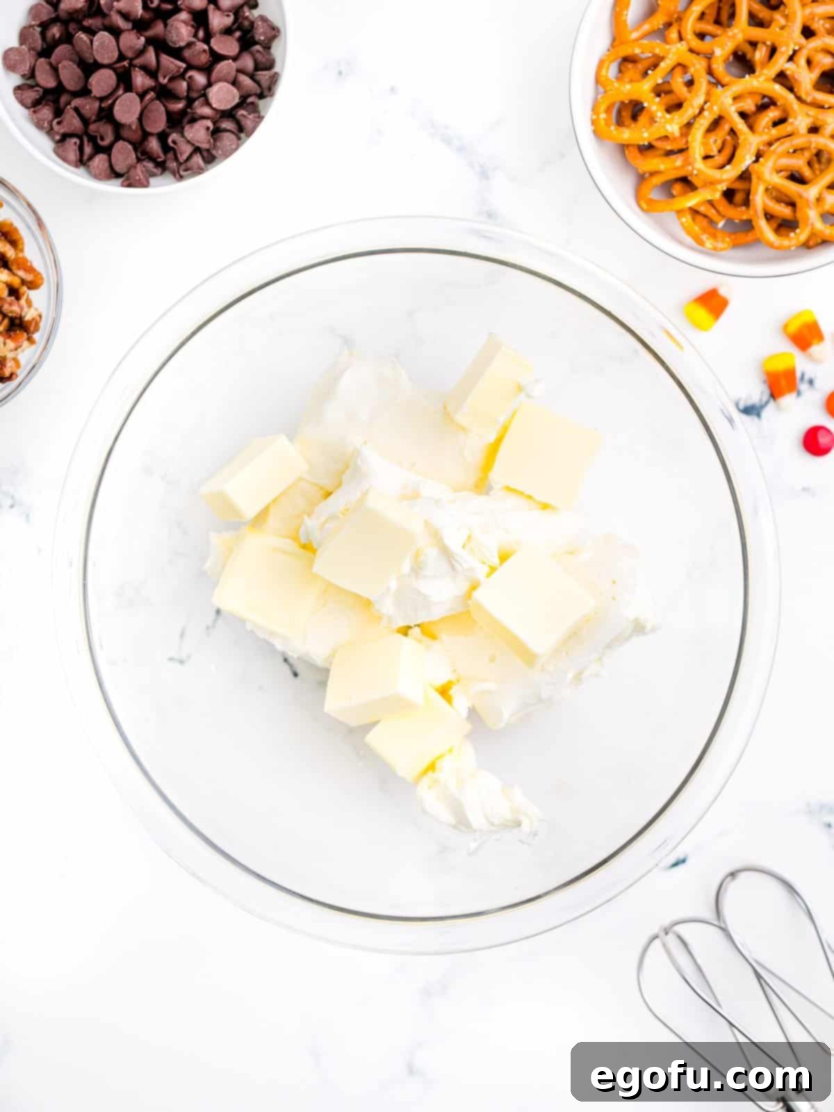Softened butter and cream cheese being creamed together in a mixing bowl until smooth.