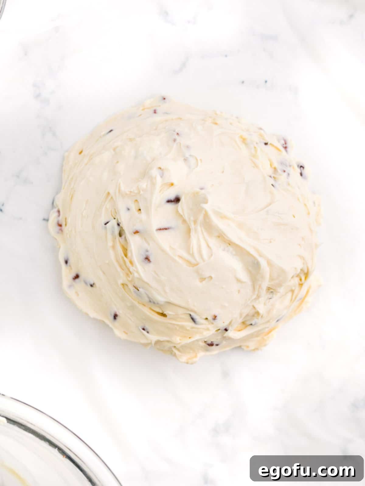 Cheeseball mixture being shaped into a smooth ball on plastic wrap, ready for chilling.