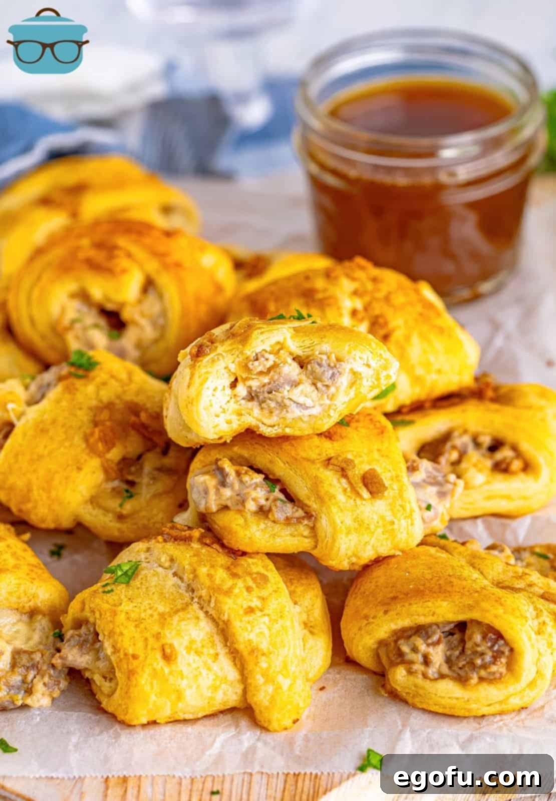 Stacked up French Dip Crescent Puffs on wooden board with bite taken out of top one.