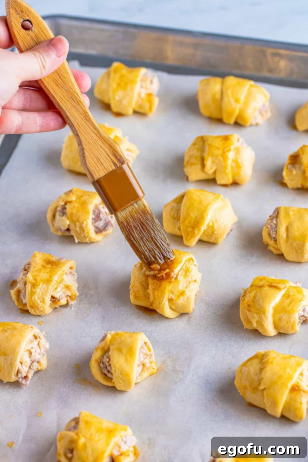 Brushing the butter and onion soup mixture over the crescents.