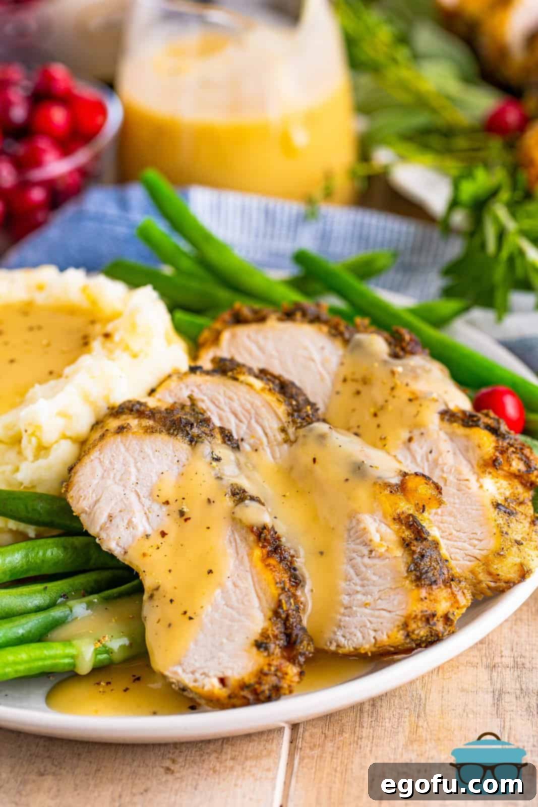 A tantalizing close-up of perfectly sliced, gravy-covered Slow Cooker Turkey Breast on a plate, emphasizing its appetizing texture and rich, homemade sauce.