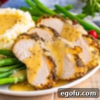 Close-up square image of gravy-covered sliced Slow Cooker Turkey Breast.