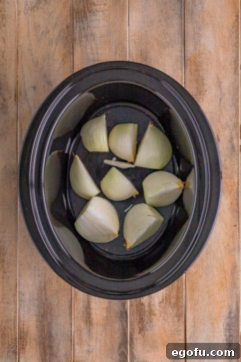 Onions placed in the bottom of a crock pot.