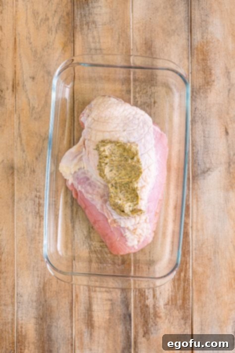 Butter mixture spread onto turkey breast in dish.