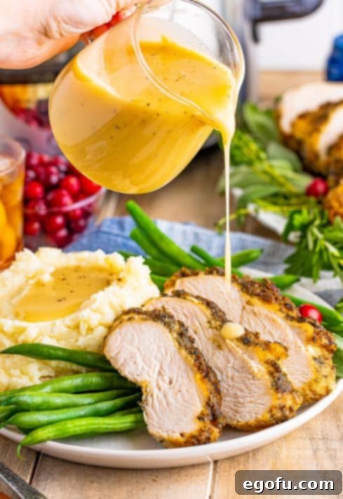 Gravy being poured over slices of Crock Pot Turkey Breast on plate with sides.