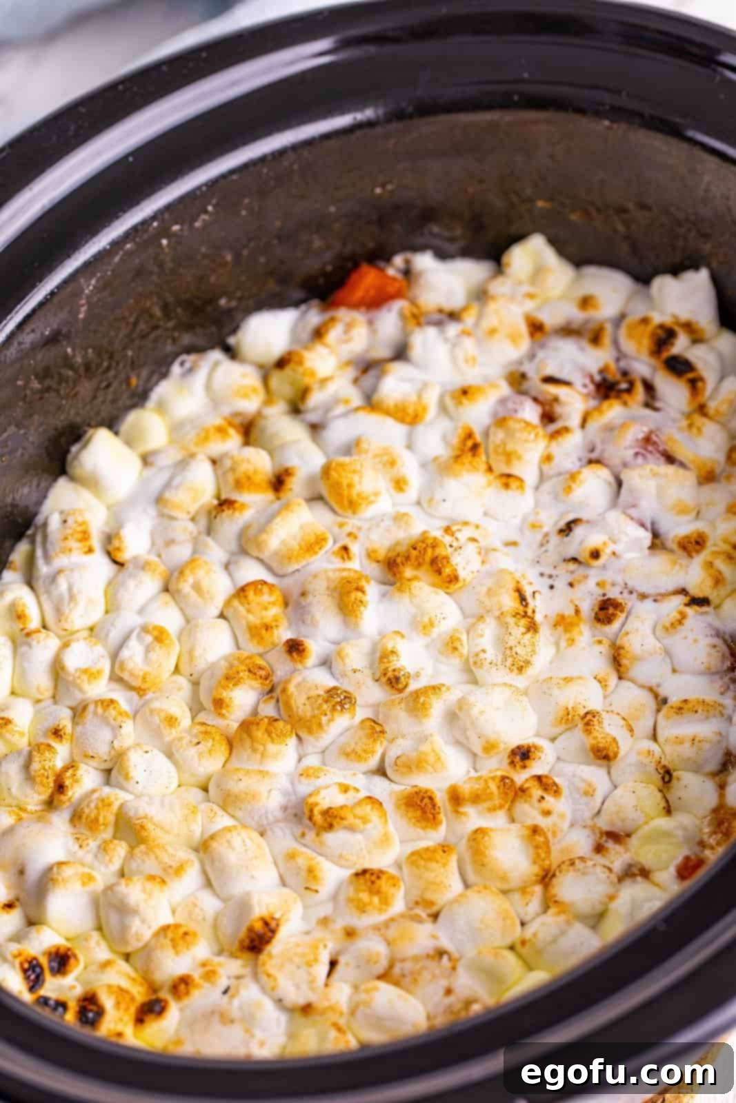 Finished Crock Pot Sweet Potato Casserole in crock pot showing browned marshmallows.