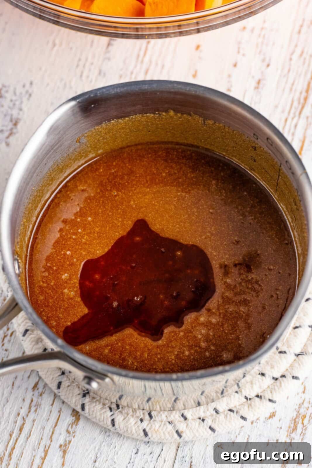 Vanilla extract added to the warm brown sugar mixture in a saucepan.