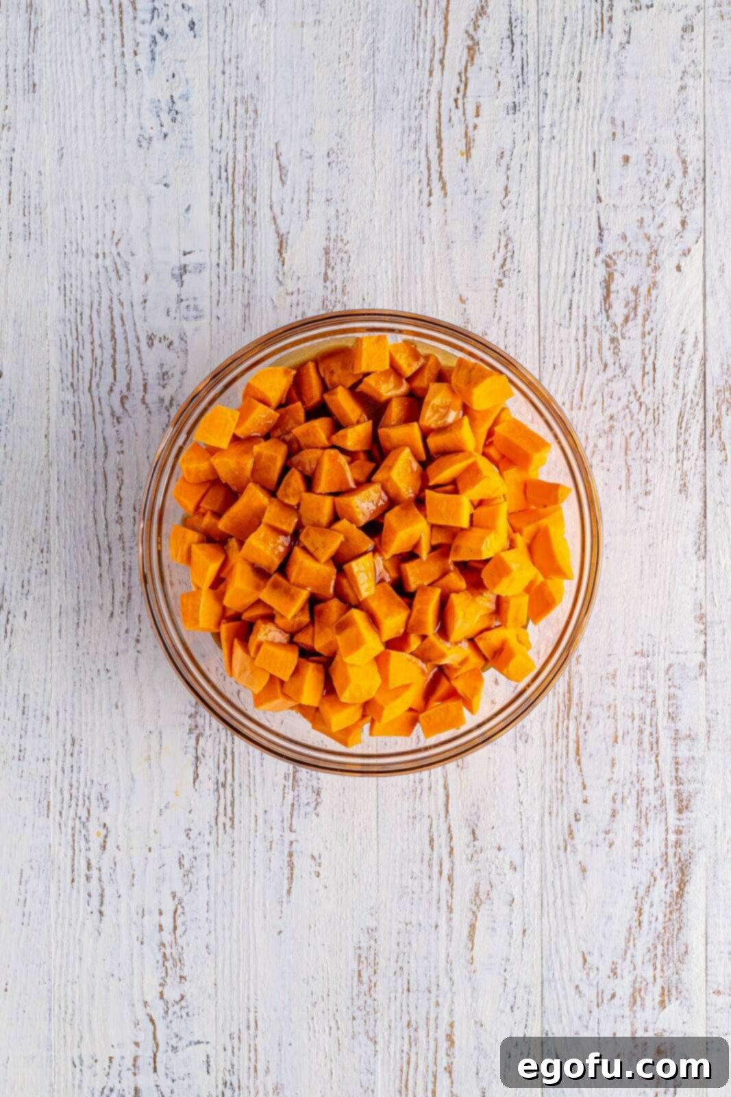 Brown sugar mixture poured over sweet potatoes in a bowl and gently stirred in.