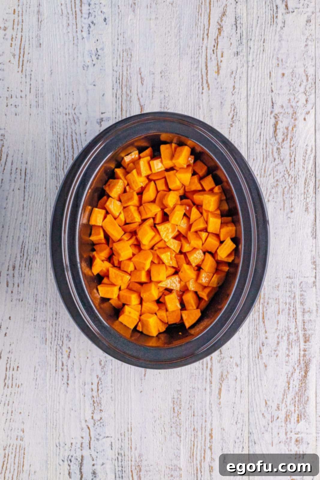 Sweet potatoes added to a slow cooker, ready for cooking.