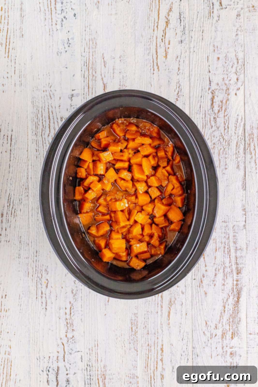 Cooked sweet potatoes in a crock pot, tender and glistening with sauce.