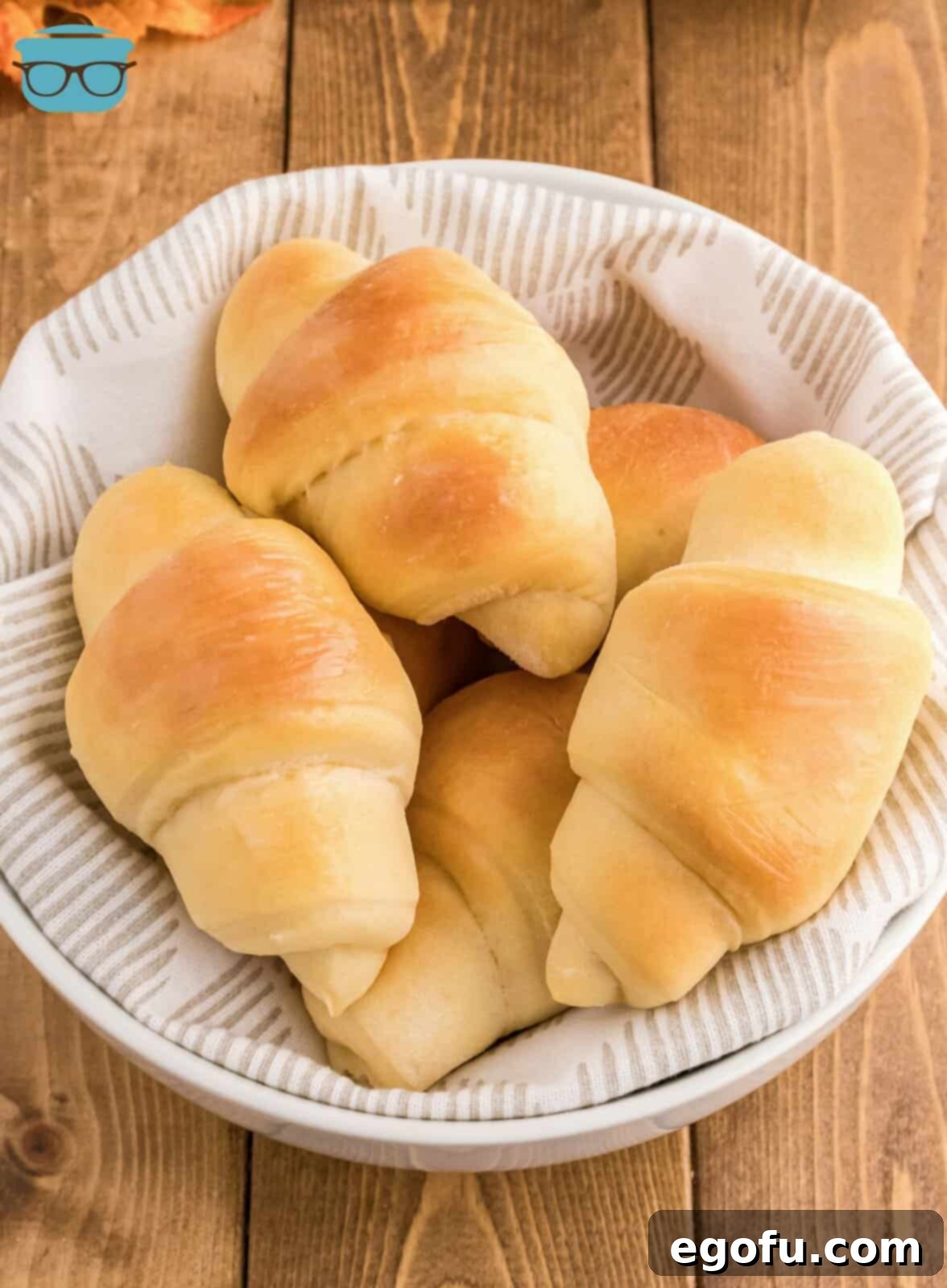 A stack of warm, fluffy Homemade Crescent Rolls nestled invitingly in a rustic linen-lined bowl, ready for the table.