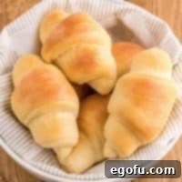Close up overhead square image of stacked Homemade Crescent Rolls in linen lined bowl.