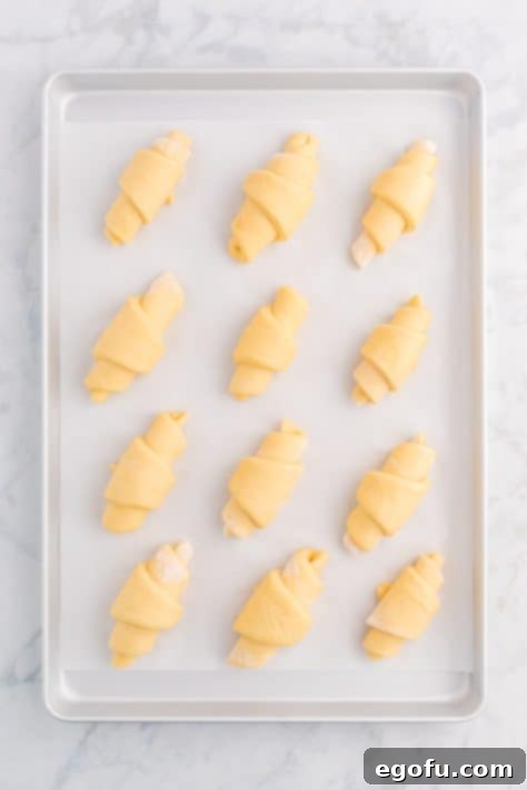 Crescent roll dough placed on lined baking sheet.