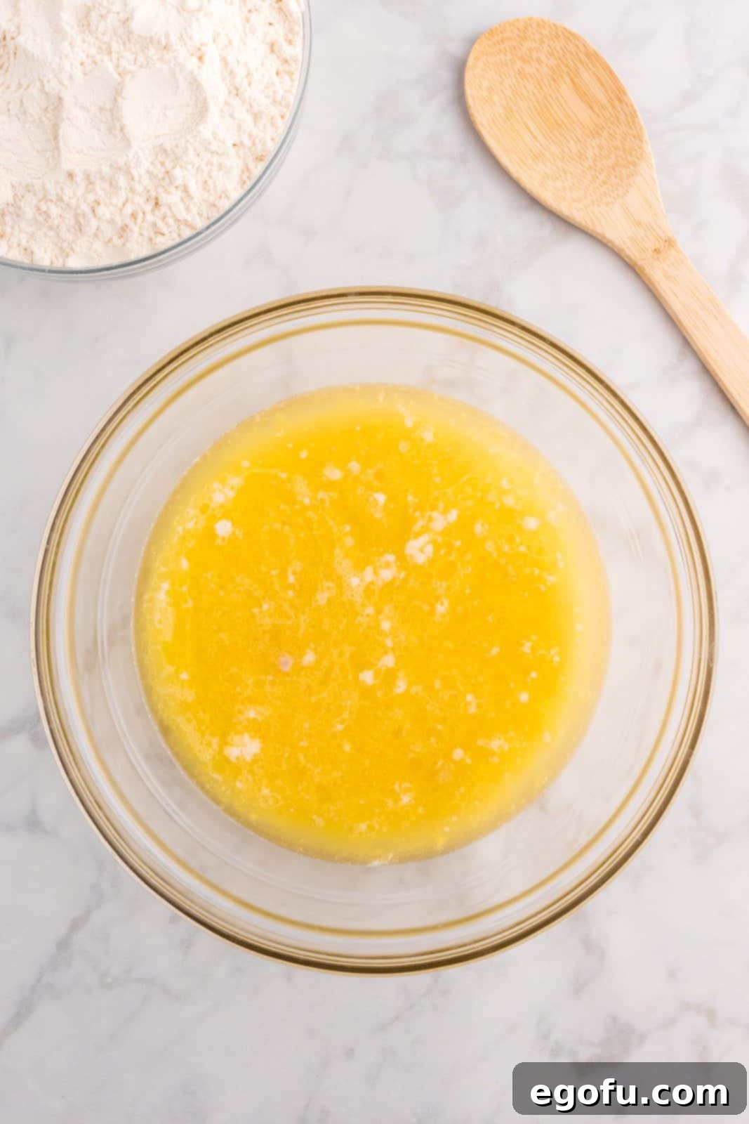 All wet ingredients—melted butter, warm water, sugar, beaten eggs, salt, and dissolved yeast mixture—being mixed together in a large bowl.