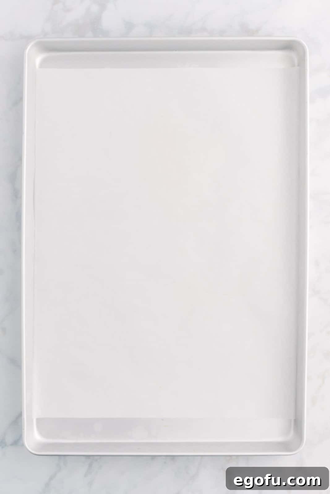 A baking sheet meticulously lined with parchment paper, preparing for the shaped crescent rolls.