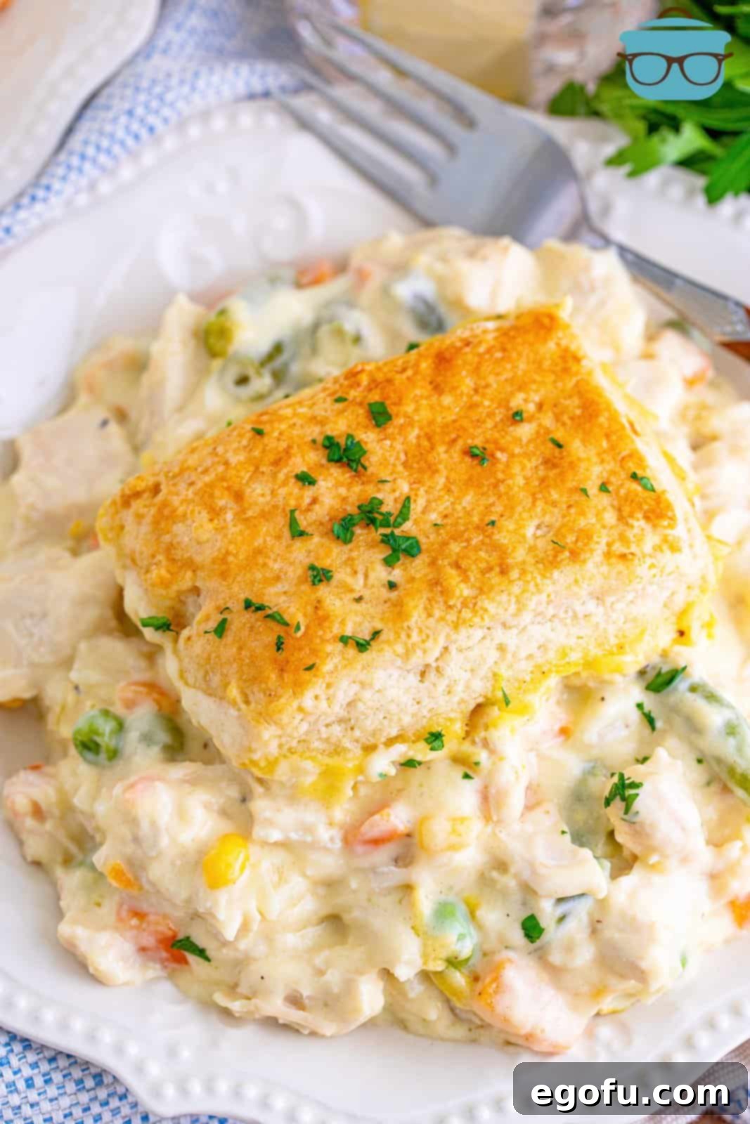 Hearty Turkey Pot Pie Delight 18 Overhead photo of Turkey Pot Pie Casserole on white plate topped with parsley.