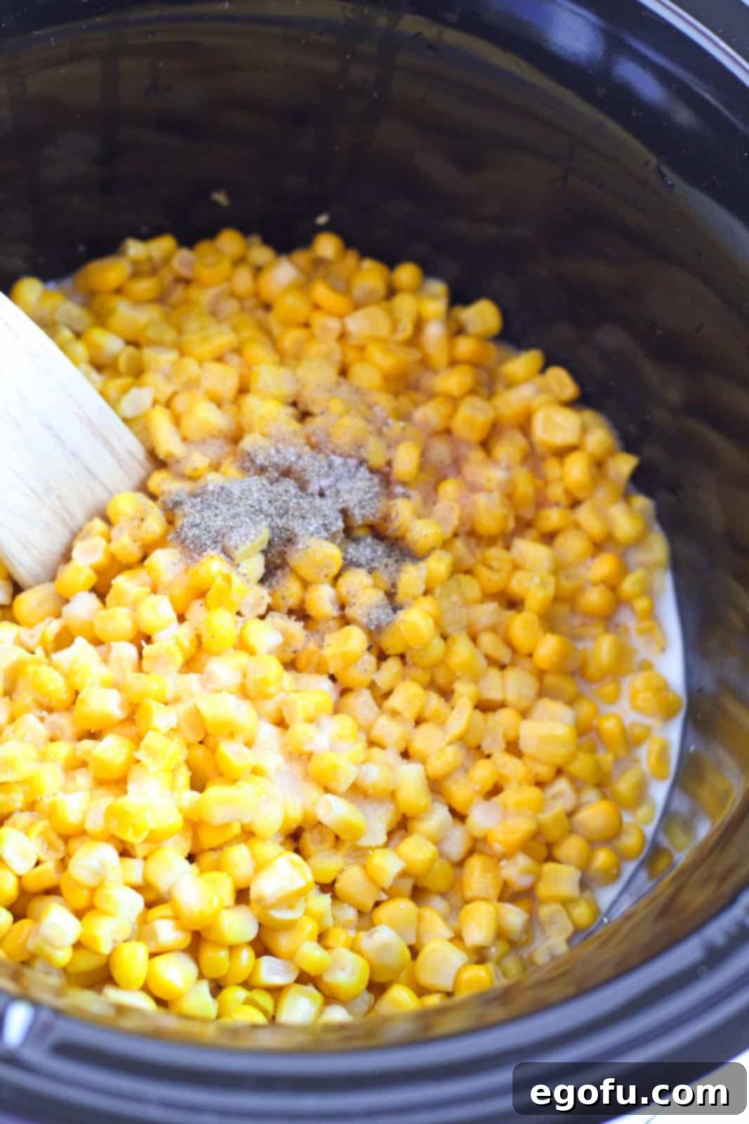 Sugar, salt and pepper added to corn in crock pot.