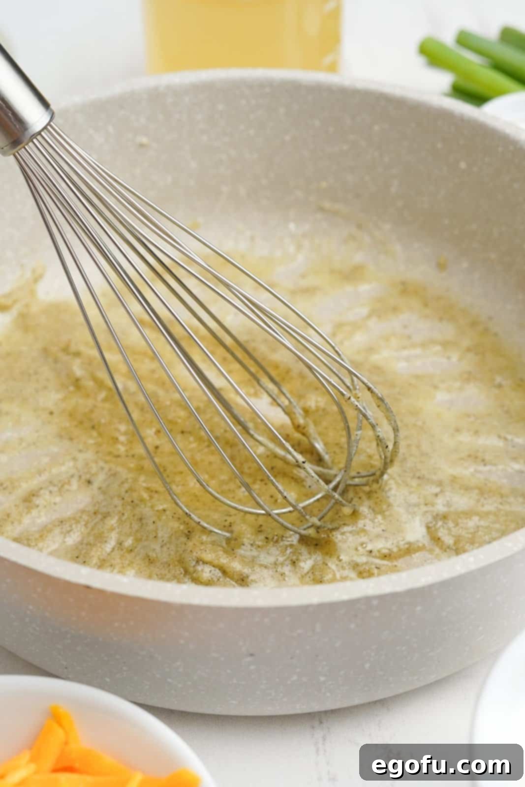 Melted butter in a pot with flour, salt, and pepper being whisked to form a roux.