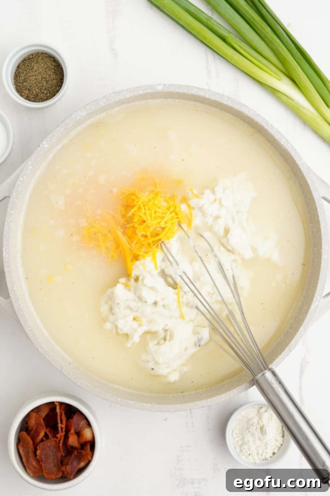 Milk, mashed potatoes, and cheddar cheese added to the pot with the soup base.