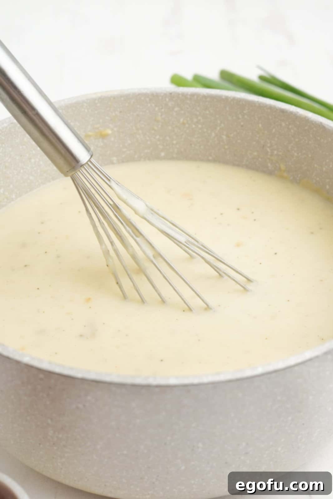 Mashed potato soup simmering in a pot, thickening to the desired consistency.