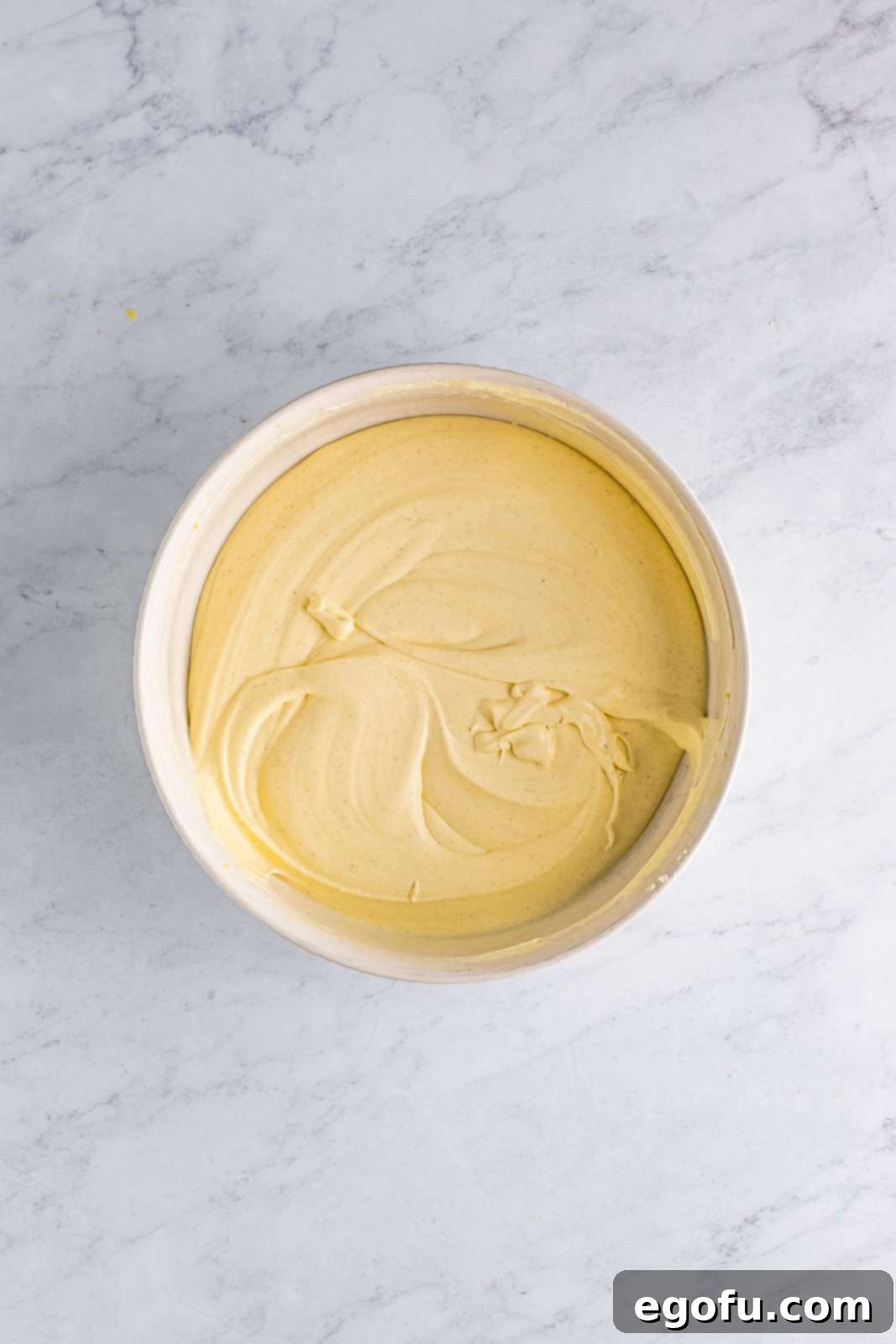 One container of whipped topping gently folded into the pudding mixture in bowl, creating a light and creamy consistency.