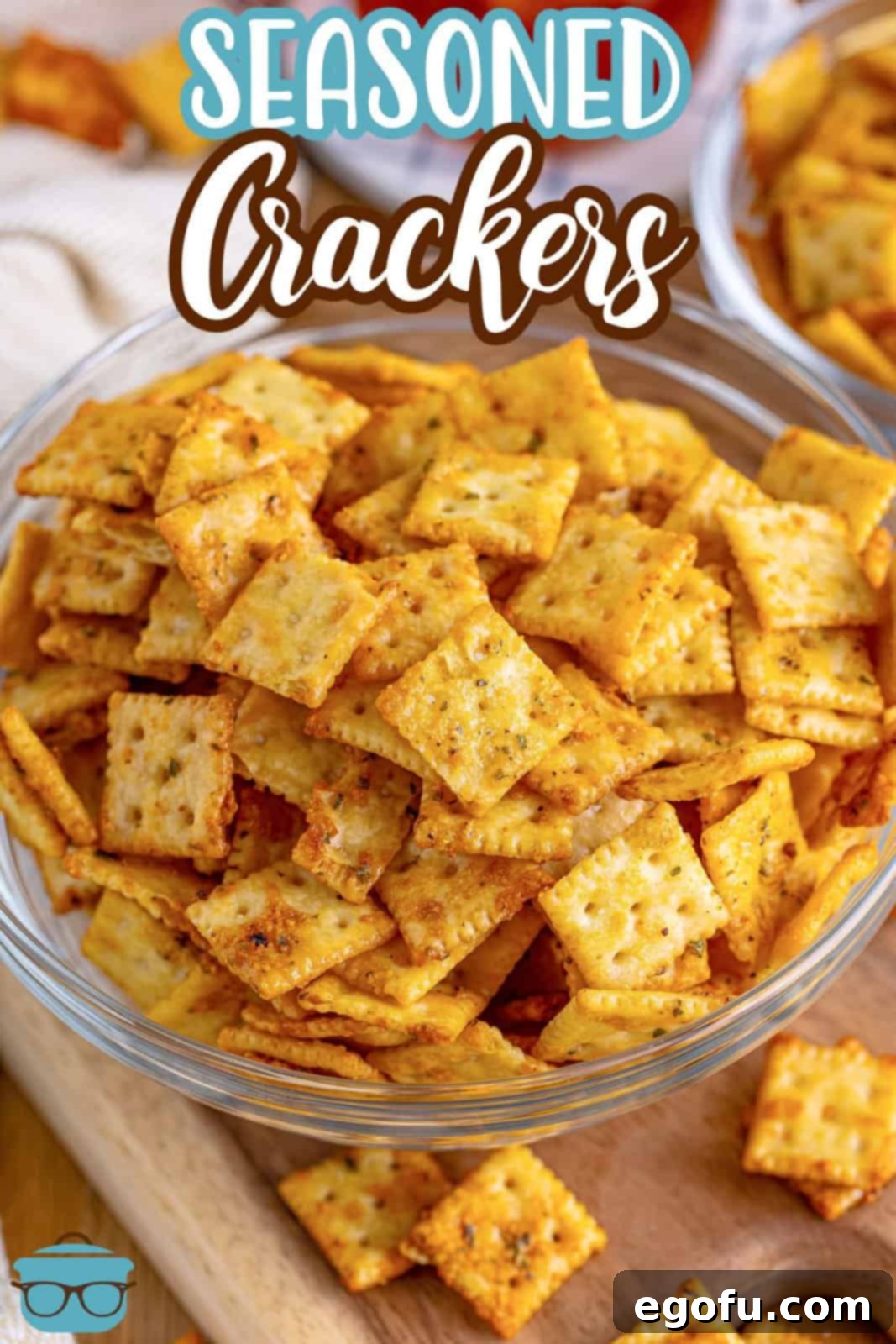 Overhead of clear bowl with Seasoned Crackers on wooden board.
