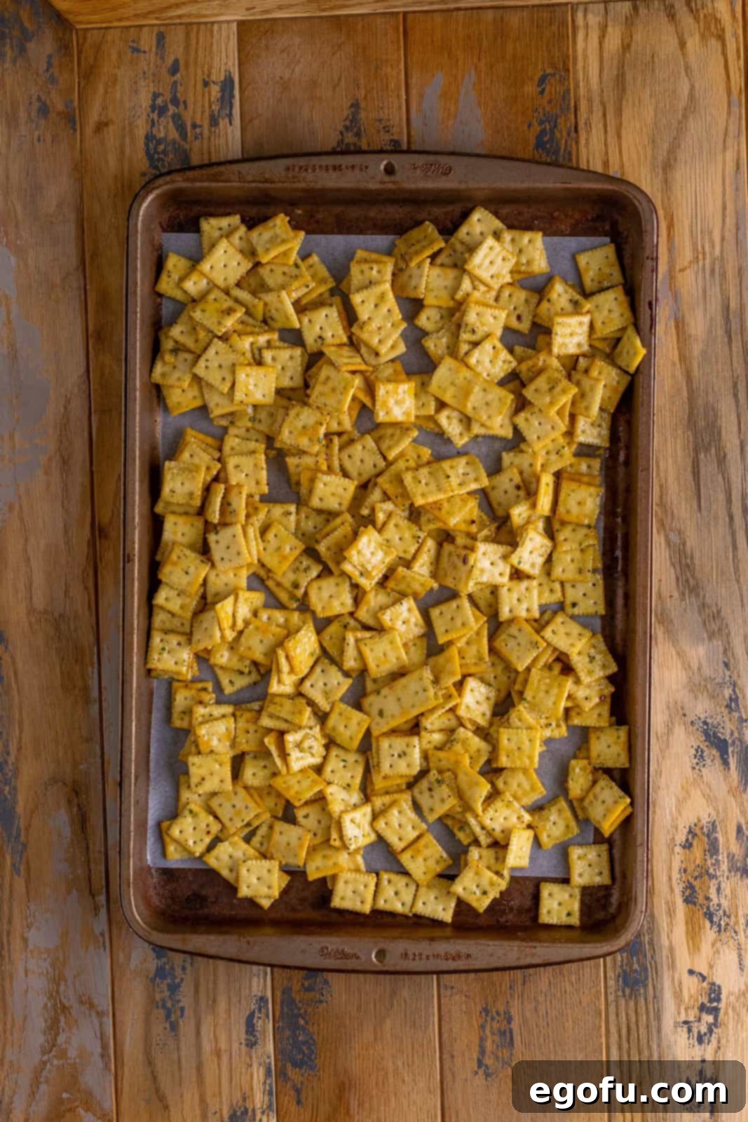 Cracker mixture spread over a parchment lined baking sheet.