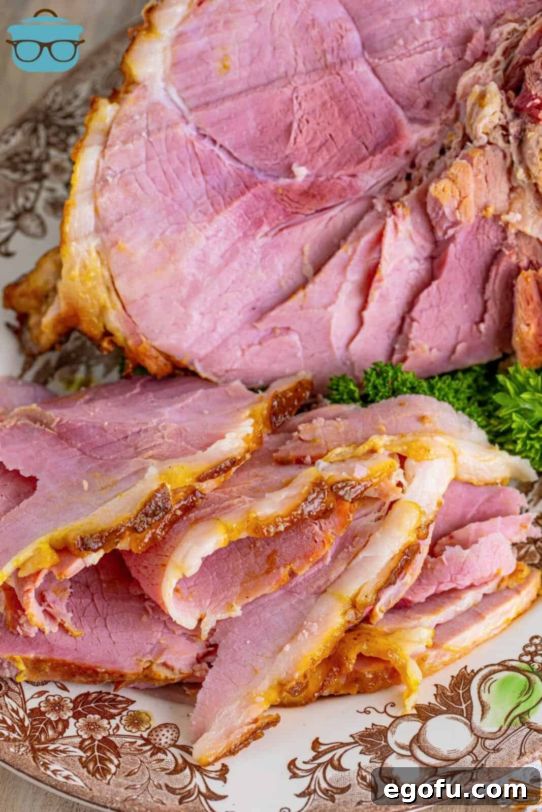 Mahogany Glazed Ham 2 Carved Brown Sugar Glazed ham on a festive plate with a whole glazed ham in the background, ready for serving.