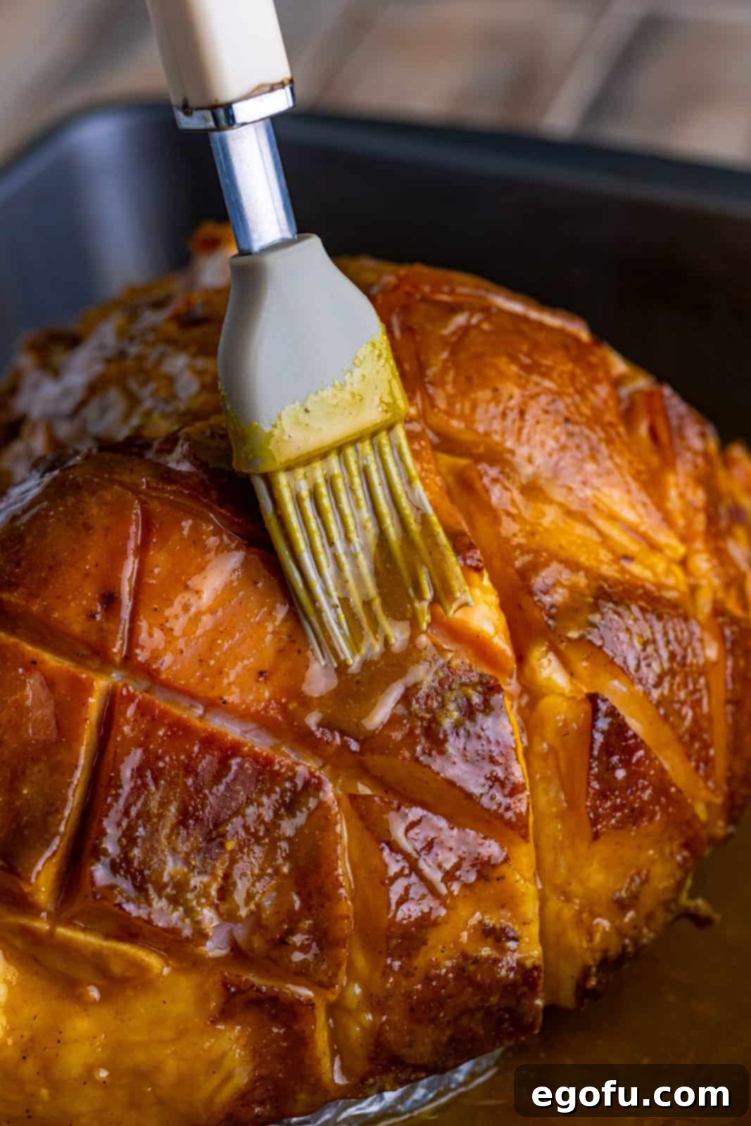 Mahogany Glazed Ham 12 A chef brushing a second layer of glaze onto the partially cooked ham in the oven.