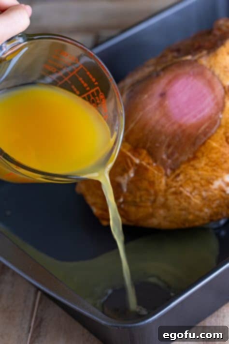 Mahogany Glazed Ham 19 Chicken stock and pineapple juice mixed together being poured into baking pan.