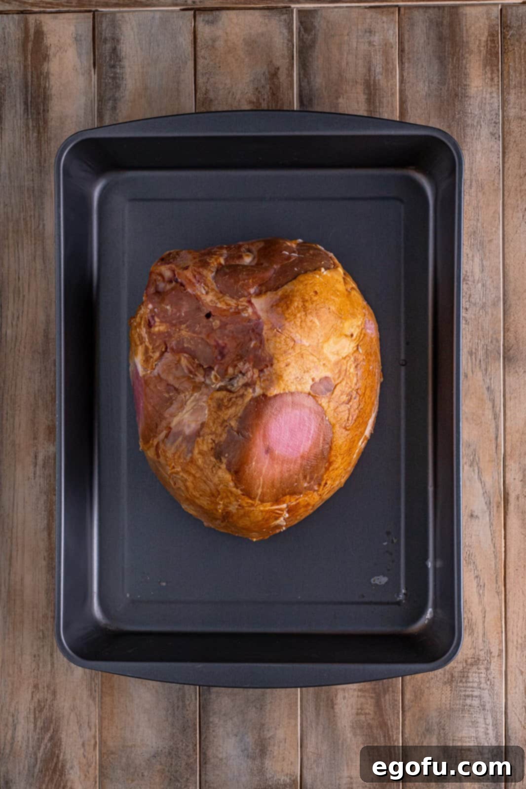 Mahogany Glazed Ham 6 A whole bone-in ham gently placed cut-side down onto the aluminum foil ring in a roasting pan.