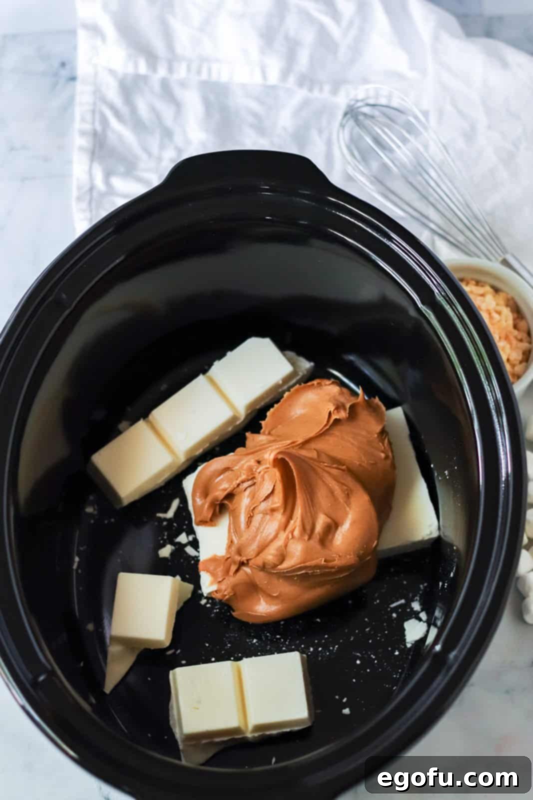 Almond bark and peanut butter added to crock pot, beginning the melting process for the cookie base.
