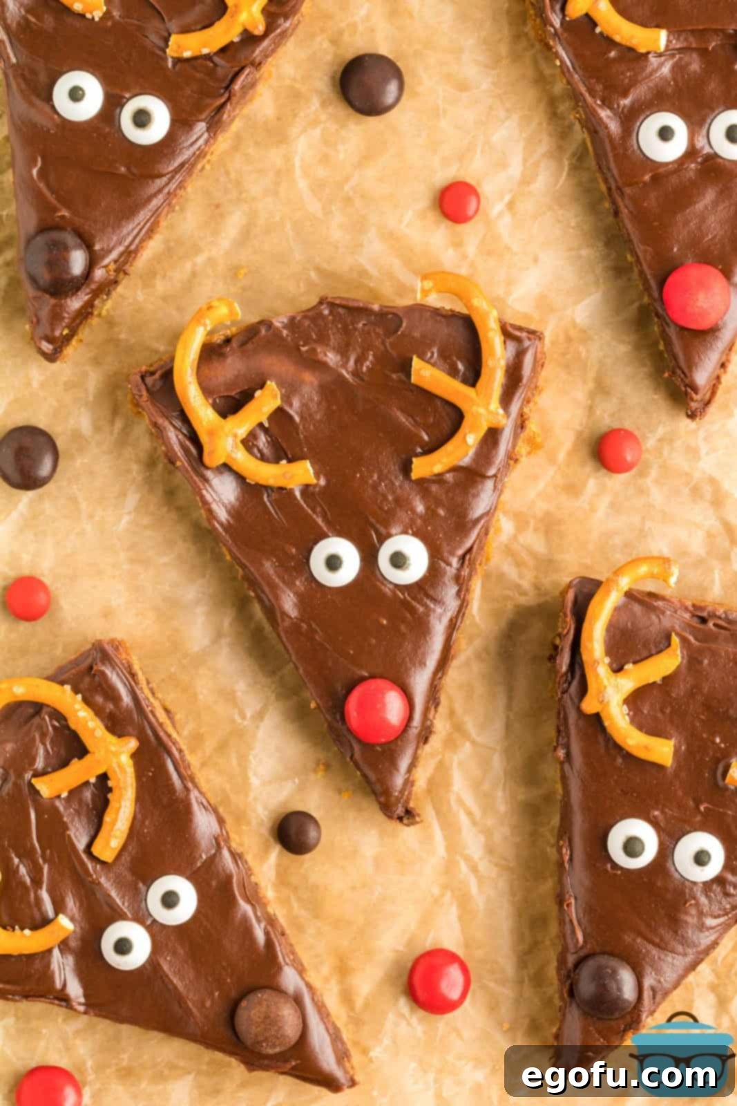 Overhead view of decorated Reindeer Cookie Bars arranged neatly on brown parchment paper, showcasing their festive appeal and readiness for serving.