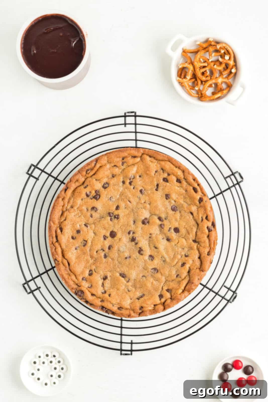 A perfectly baked, round cookie base, golden-brown and set, resting on a wire rack to cool completely before the frosting and decorating steps.