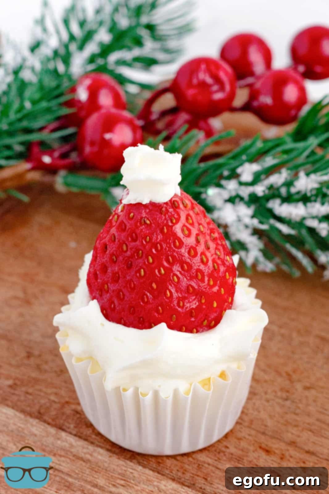 Jolly Santa Hat Cheesecakes 2 One of the Santa Hat Mini Cheesecakes on wooden board with decorations in background.