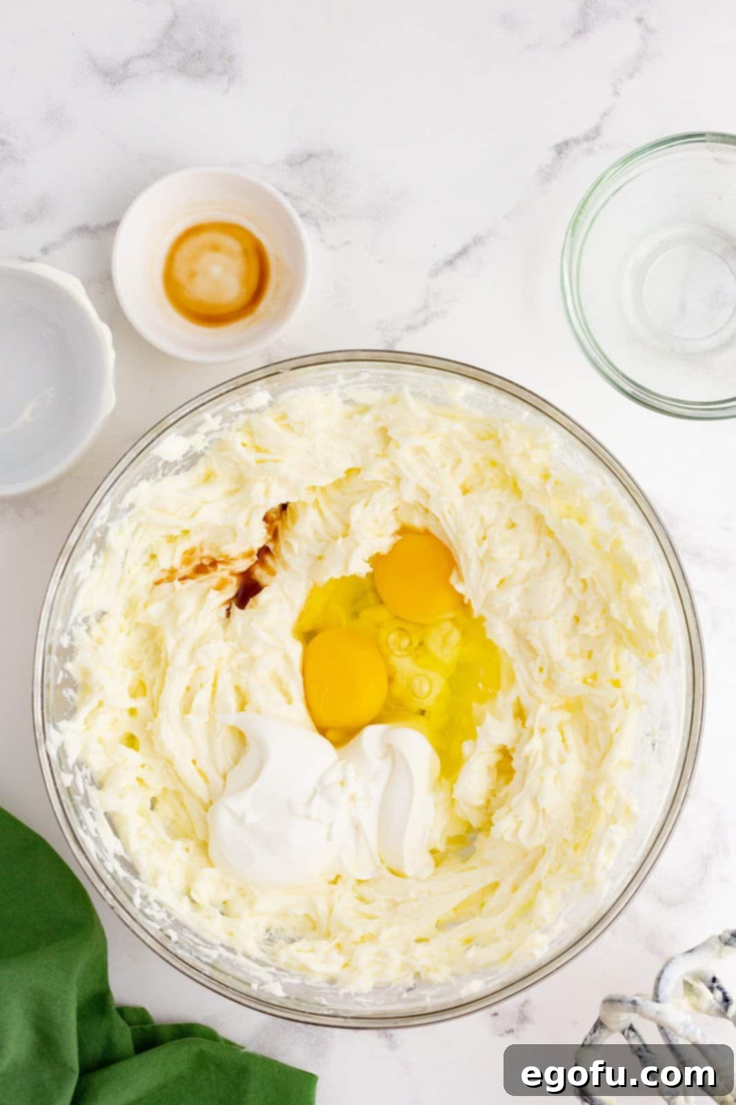 Jolly Santa Hat Cheesecakes 8 Eggs, sour cream and vanilla added to beaten cream cheese and sugar.