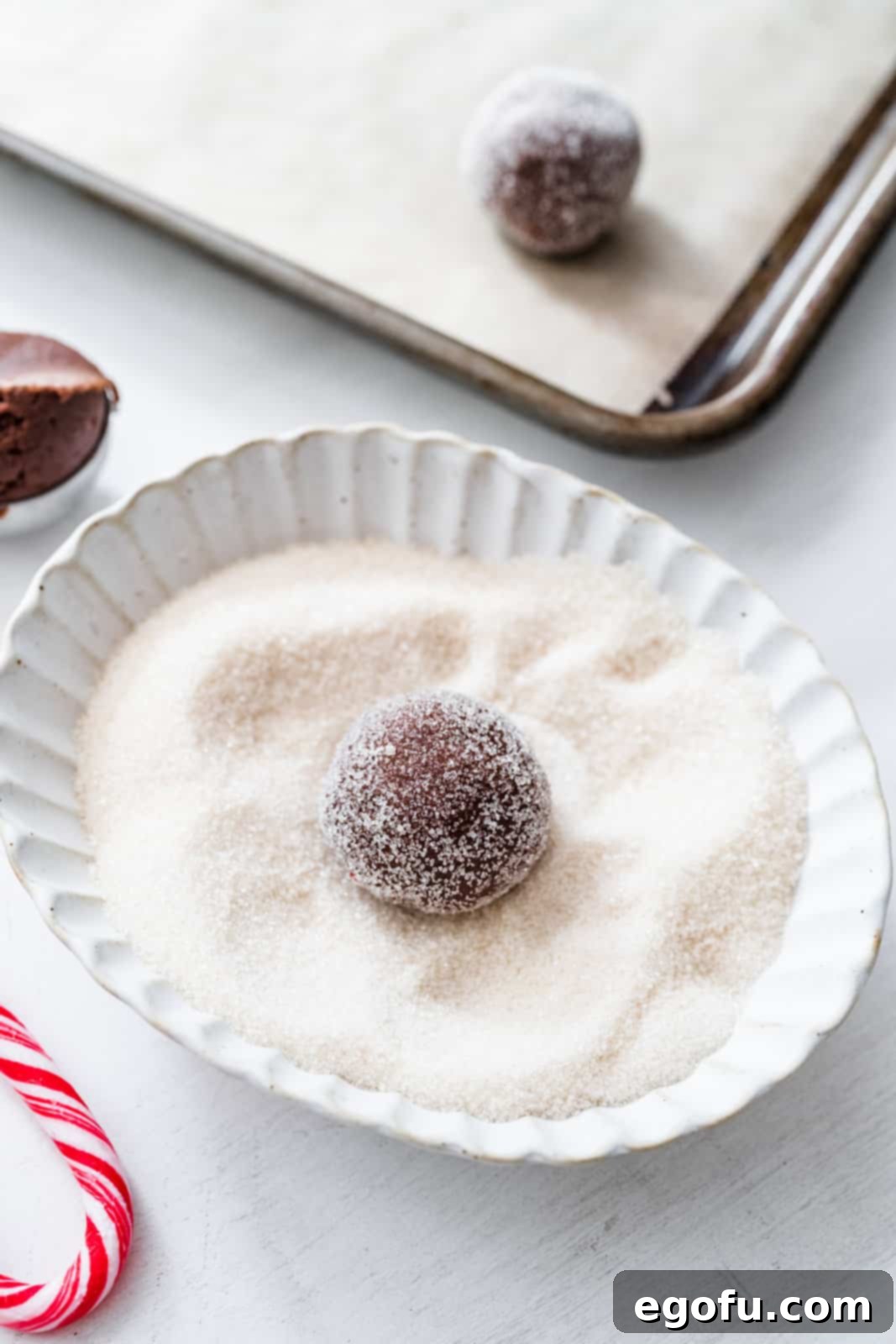 Cookie dough ball being rolled in sugar.
