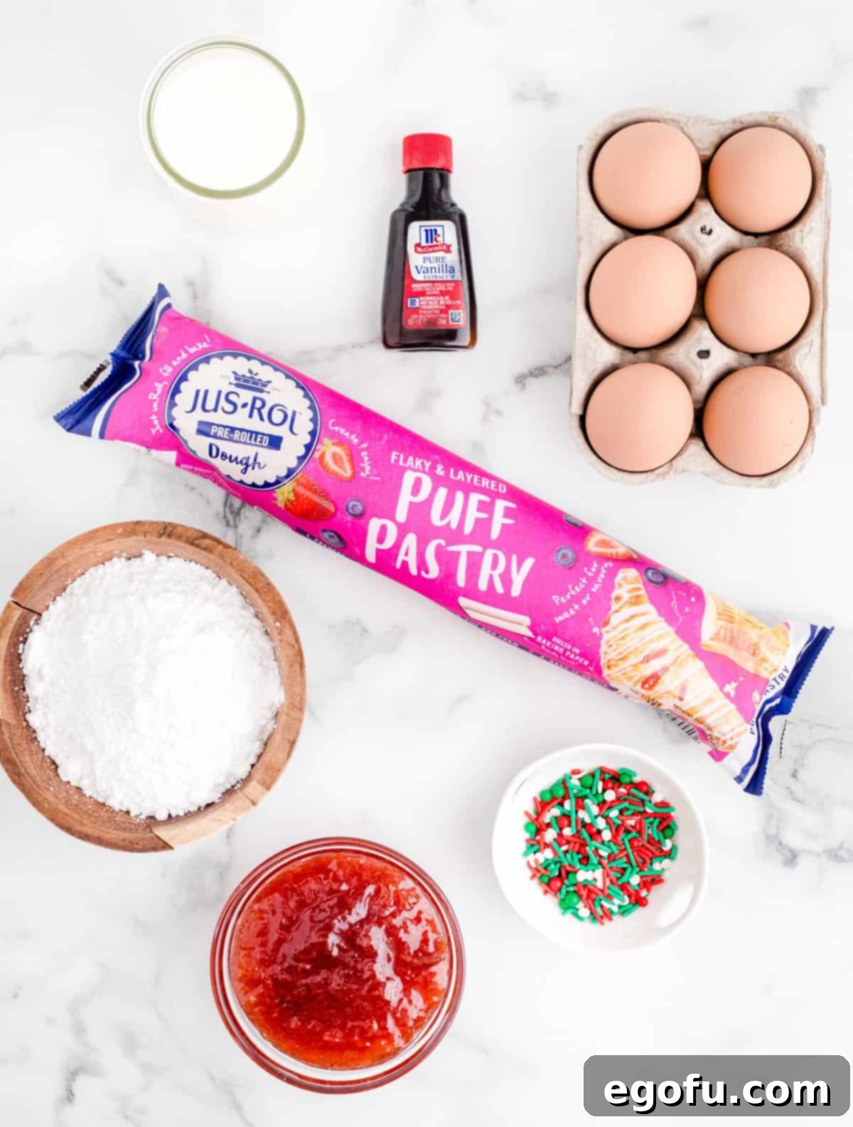 Sparkling Spruce Pop Tarts 4 Ingredients for Christmas Tree Pop Tarts laid out: puff pastry, strawberry preserves, egg, powdered sugar, milk, vanilla extract, and holiday sprinkles.