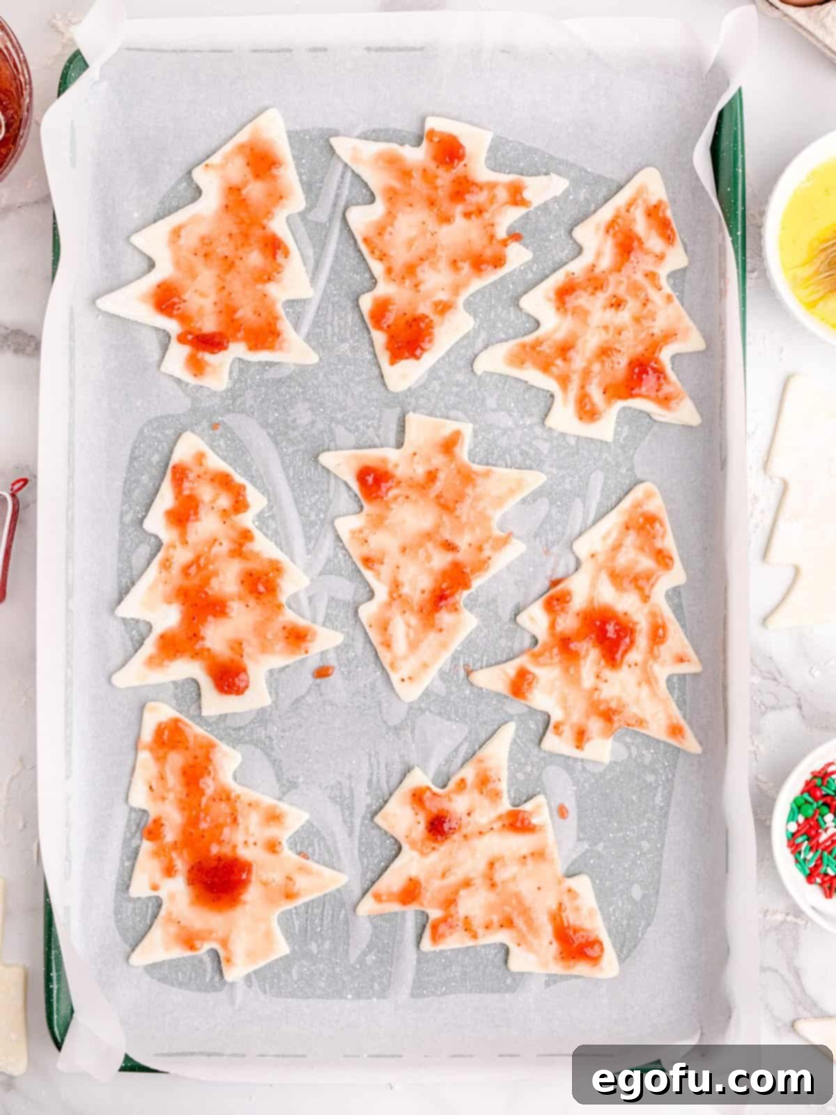 Sparkling Spruce Pop Tarts 6 Strawberry preserves spread evenly over the bottom layer of puff pastry Christmas tree shapes on parchment paper.