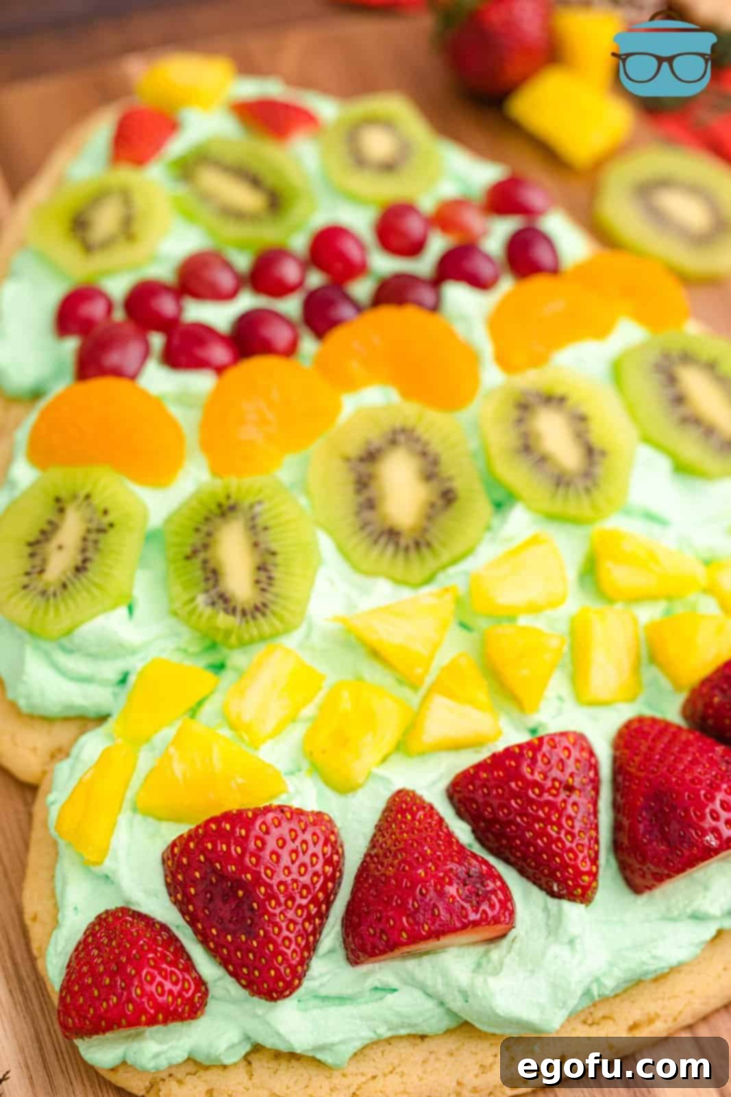 A close-up view of the finished Christmas Tree Fruit Pizza, showcasing the meticulously arranged colorful fruits on the green whipped cream.