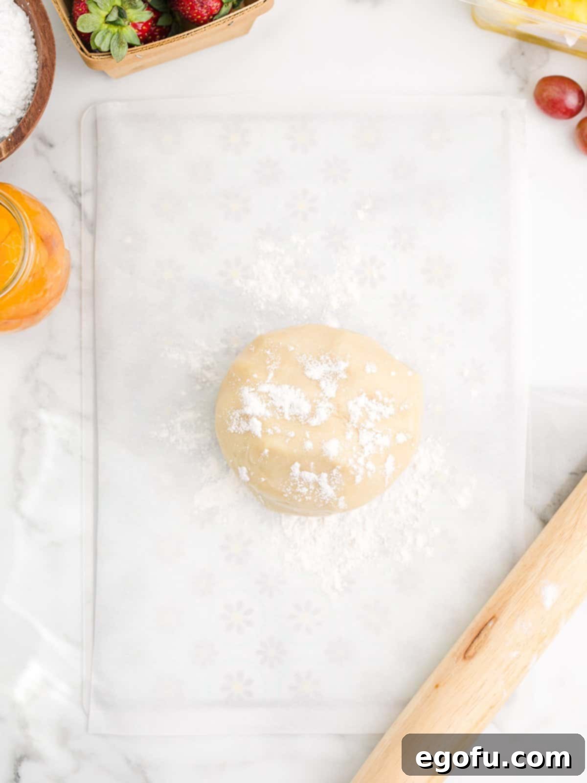 Cookie dough formed into a ball, lightly dusted with flour, on parchment paper.