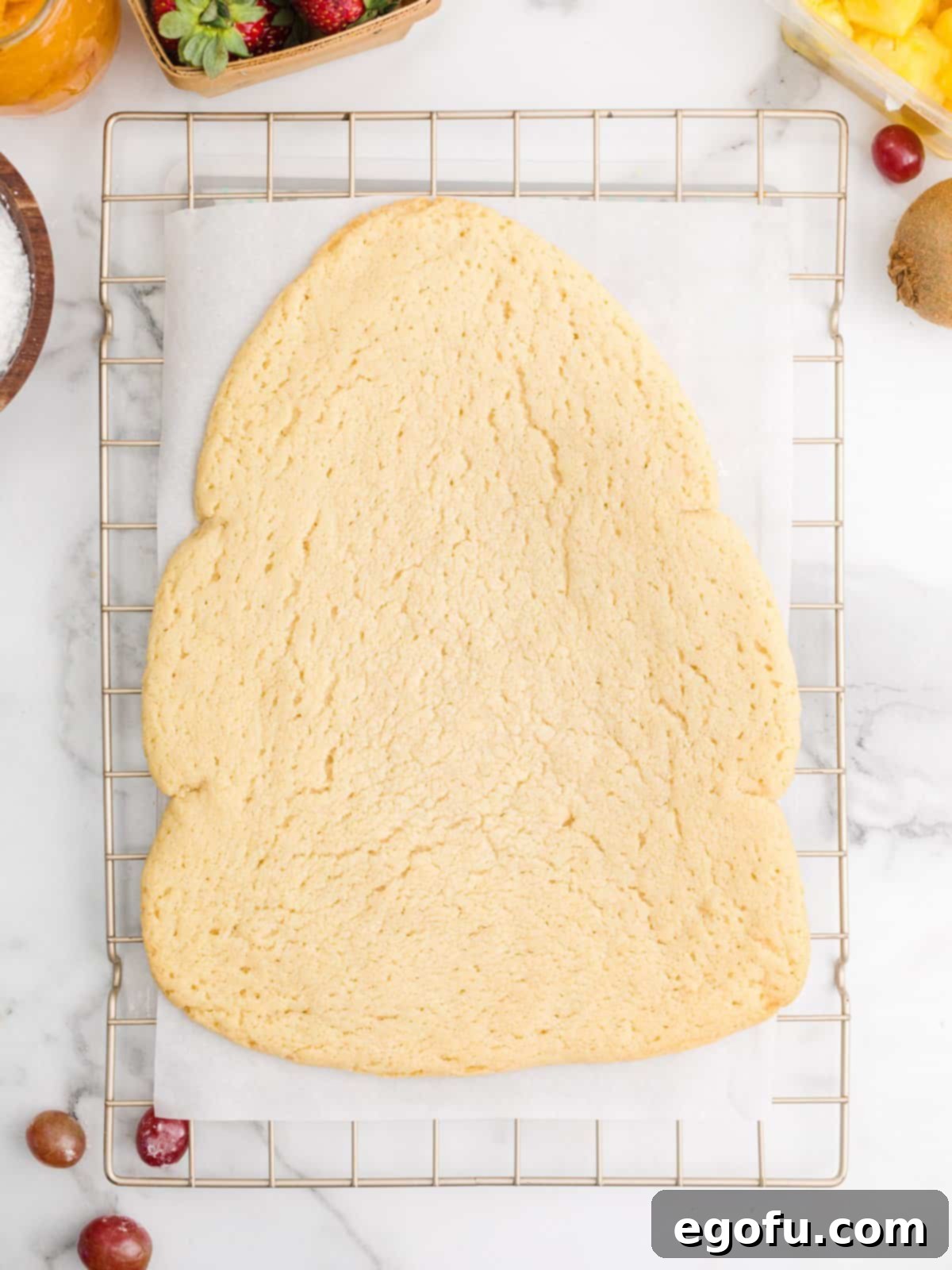 A perfectly baked Christmas tree-shaped sugar cookie resting on a wire rack after being removed from the oven.