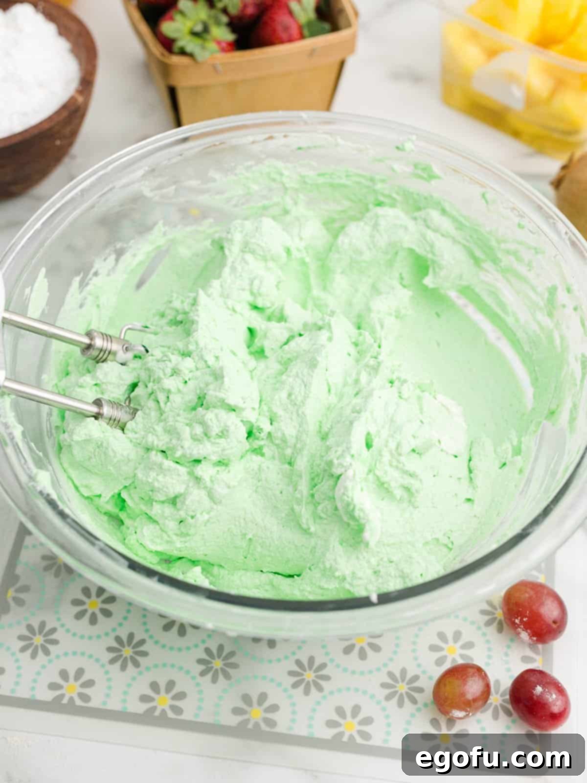 Freshly mixed green whipped cream in a large bowl, showing its light and fluffy texture, ready to be spread.