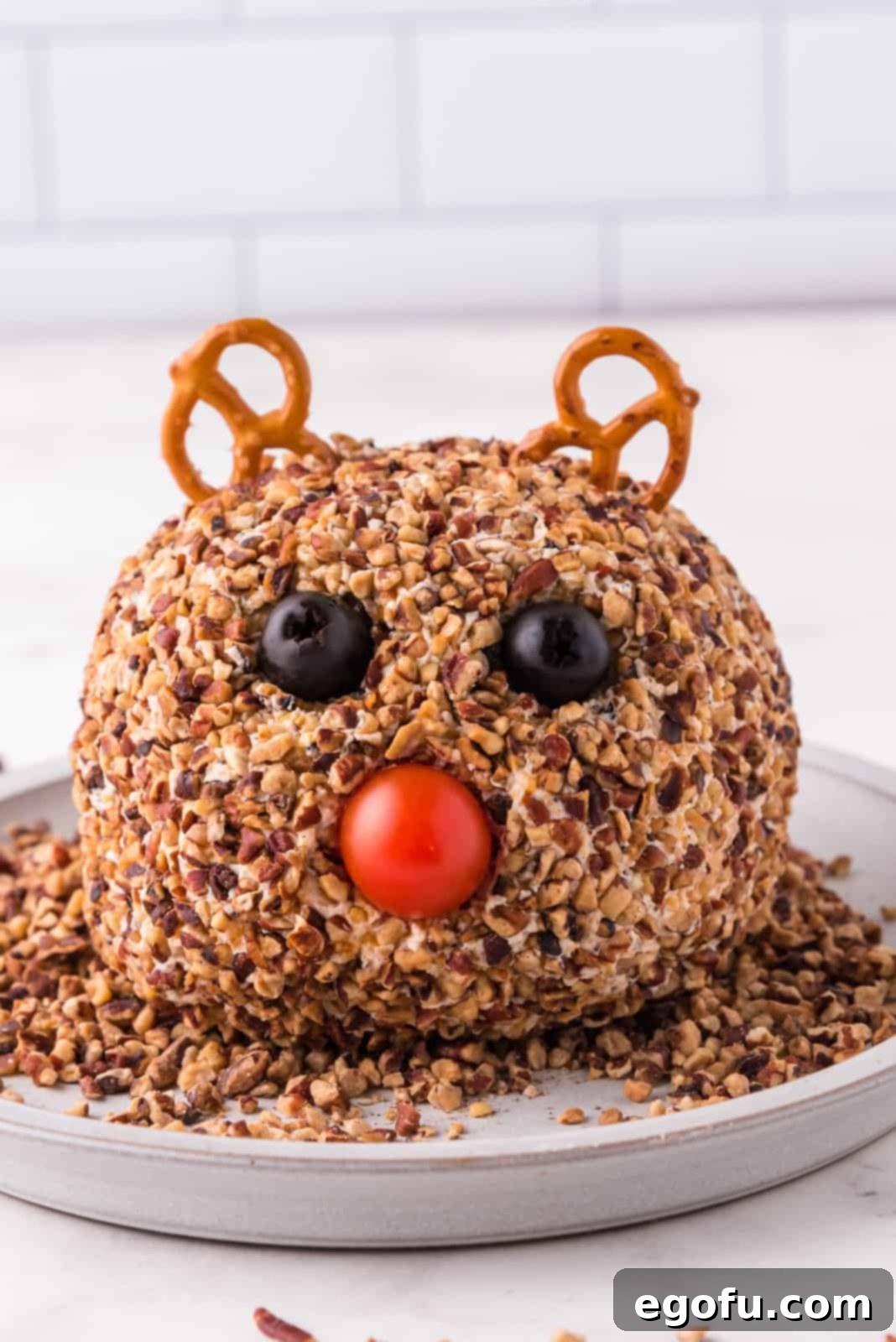 Pretzels, black olives, and a cherry tomato added to the cheeseball to form Rudolph's festive face.
