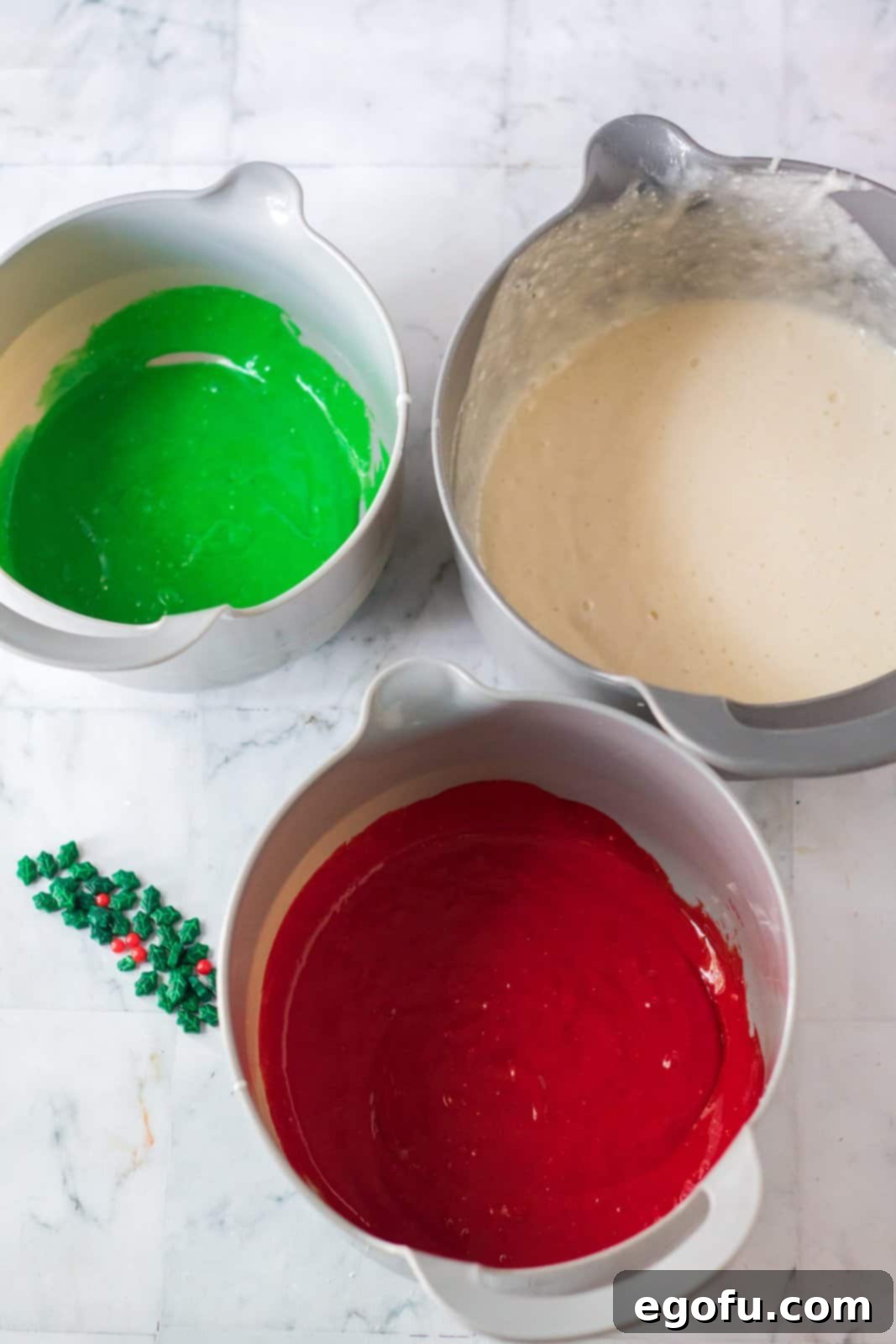 three bowls with each holding different colored cake batter: white, red and green.